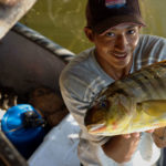 Man in canoe holding up a fish